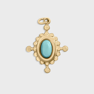 Gold compass pendant with a turquoise stone on a light gray background