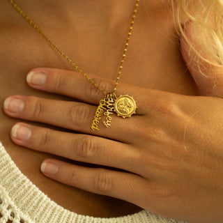 Gold necklace with a pendant on a person's hand