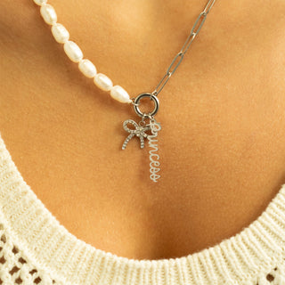 Necklace with a bow and 'love' charm worn by a person