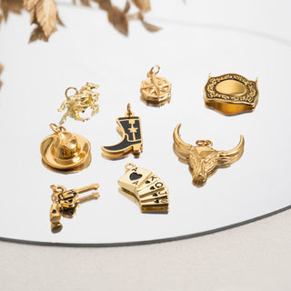 Collection of gold western pendants on a reflective surface with a neutral background