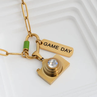 Gold necklace with 'GAME DAY' tag and heart-shaped pendant on a white background