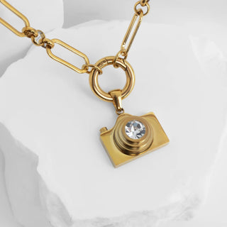 Gold camera-shaped pendant necklace on a white background