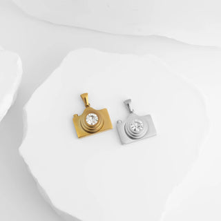 Gold and silver camera-shaped pendants on a white background