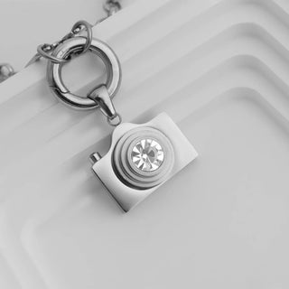 Silver camera-shaped pendant necklace on a white background