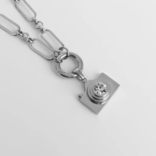 Silver chain necklace with a unique pendant on a light gray background