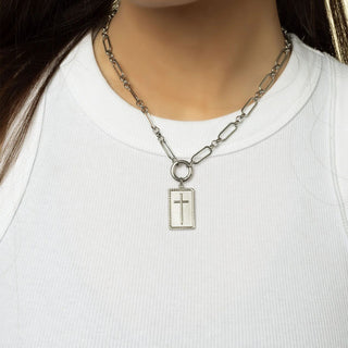 Silver necklace with a cross pendant on a white shirt