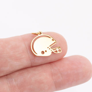 Gold helmet-shaped pendant on a hand against a white background