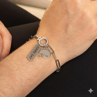 Silver bracelet with charms on a wrist against a neutral background