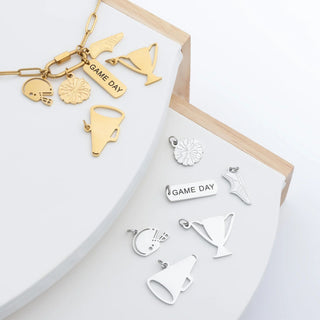 Collection of gold and silver charms on a white surface with a wooden frame.