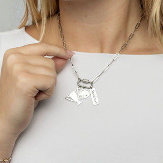 Person wearing a silver necklace with multiple pendants on a plain background