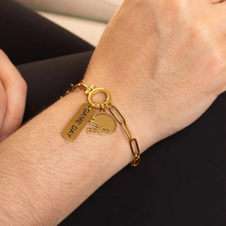 Gold bracelet with charms on a wrist against a black background