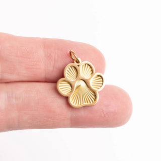 Gold paw print charm held between fingers on a white background