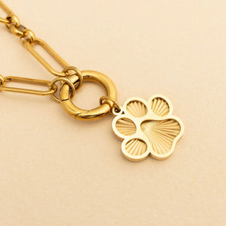 Gold chain necklace with a paw-shaped pendant on a beige background