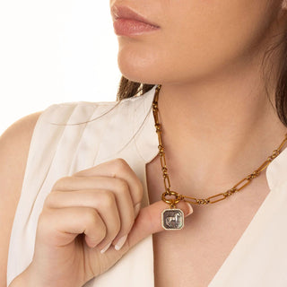 Close-up of a woman wearing a gold necklace with a pendant.