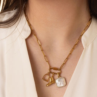 Gold necklace with charms on a person wearing a white blouse