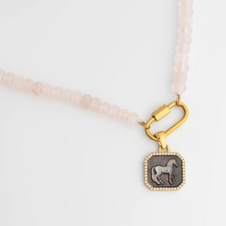 Necklace with a gold clasp and horse pendant on a light background