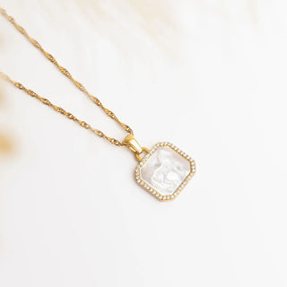 Gold necklace with a square pendant on a white background
