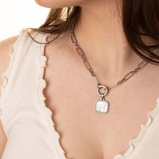 Necklace with a pendant worn by a person, close-up on a neutral background