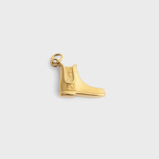 Gold equestrian boot pendant on a light gray background
