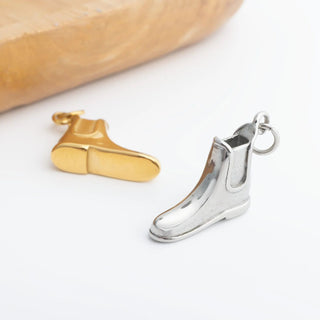 Silver and gold equestrian boot charms on a white surface