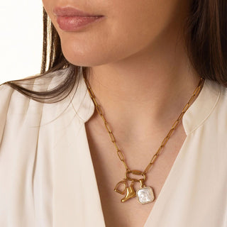 Gold necklace with equestrian charms worn by a person against a neutral background
