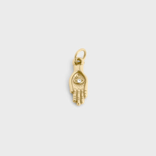 Gold charm shaped like a hand with an eye design on a light gray background