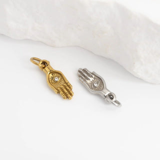 Gold and silver hand-shaped charms on a white fabric background