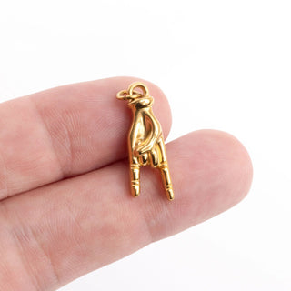 Gold hand-shaped charm held between fingers on a white background