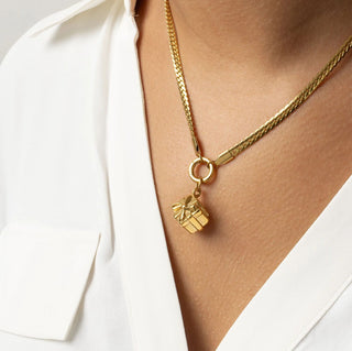 Gold necklace with a gift box pendant on a white background