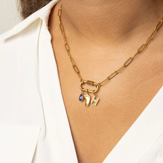 Gold chain necklace with charms on a person wearing a white shirt