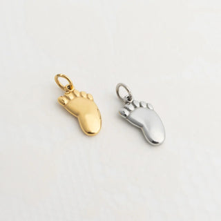 Gold and silver foot charm on a light gray background