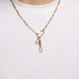 Gold necklace with a whisk pendant on a white background