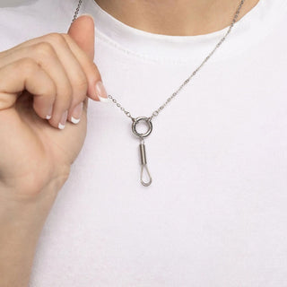 Silver necklace with a unique pendant held by a hand against a white background