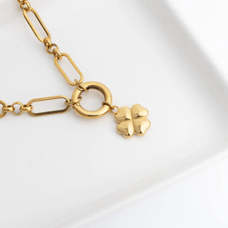 Gold bracelet with a clover charm on a white background