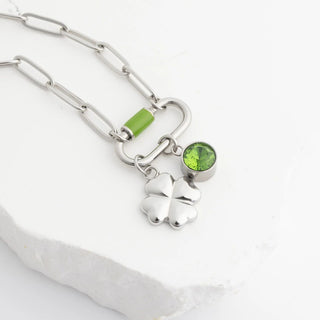 Silver necklace with green gemstones on a white background
