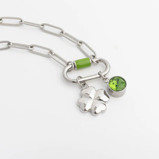 Silver chain bracelet with clover charm and green gemstones on a white background