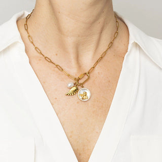 Person wearing a gold necklace with charms on a white background