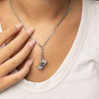 Silver necklace with a dice pendant worn by a person wearing a white shirt