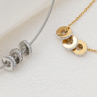 Gold and silver necklaces with spacer beads on a textured white surface