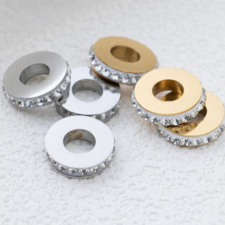 Spacer beads with rhinestone embellishments on a textured white surface