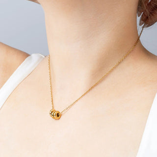 Gold necklace with a spacer beads on a person wearing a white top against a light gray background
