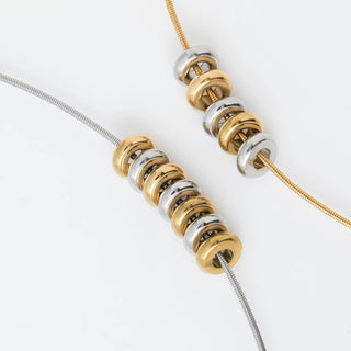 Close-up of gold and silver spacer beads on a necklace on a white background