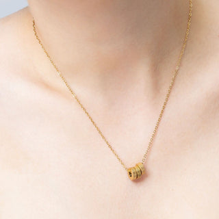 Gold necklace with spacer beads on a person's neck against a neutral background