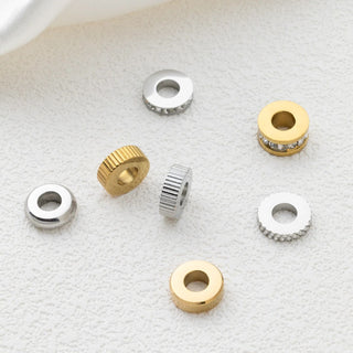 Gold and silver spacer beads on a textured white surface