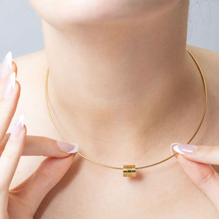 Gold necklace being worn on a person's neck with a neutral background