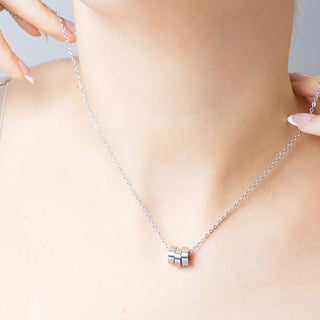 Silver necklace with spacer beads on a person's neck against a neutral background