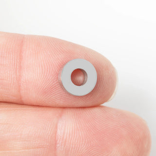 Small spacer bead held between fingers against a white background