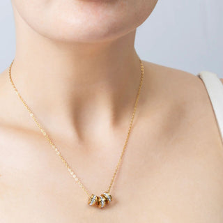 Gold necklace with spacer beads on a person against a neutral background