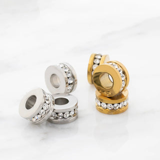 Silver and gold spacer beads with clear stones on a white background