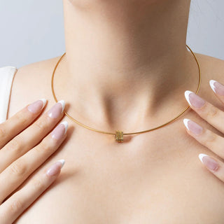 Gold necklace being worn on a person's neck with a plain background